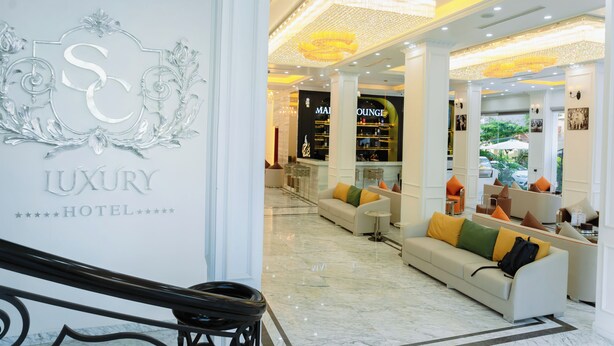 A luxury hotel lobby with a marble floor, a reception desk, and a lounge area with sofas and chairs. - SC Luxury Hotel (Bai Chay)