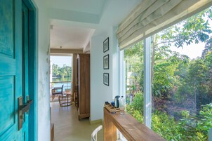 Una habitación con un escritorio de madera, vistas a la vegetación y una puerta con marco azul.