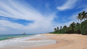 A beach with clear skies, calm waters, and palm trees. - 33 Lake Terrace  (Hikkaduwa)