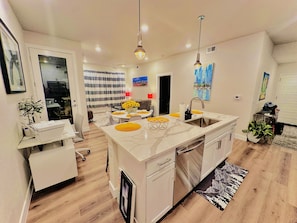 Een moderne keuken met een centraal eiland, witte kastjes en een eethoek met gele placemats.