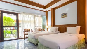 Habitación de hotel con dos camas, una ventana con cortinas, una silla y un cuadro en la pared.