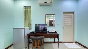 Habitación compacta con escritorio, silla, televisión, equipo de aire acondicionado y una puerta.