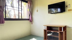 Una habitación con un amplio ventanal, un televisor de pantalla plana montado en la pared y un mueble de madera con puerta de vidrio.