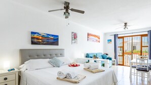 A hotel room with a large bed, a ceiling fan, a balcony with a view, and artwork on the walls. - Port Royale shine and bright, heated pool (Los Cristianos)