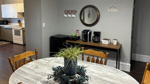 Un comedor con una mesa redonda, sillas, un florero con follaje, una cafetera y un cartel que dice "FILTERS".
