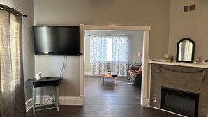 Una sala de estar con televisor de pantalla plana, chimenea y zona de comedor con mesa y sillas.