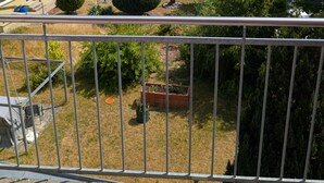Een woonwijk met meerlaagsgebouwen, een verzorgde tuin en een metalen balkonhek.