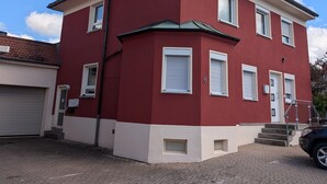 Een rode en witte, twee verdiepingen tellende woning met schoorsteen, schotelantenne en garage.