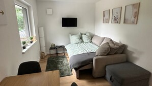 Ein modernes Schlafzimmer mit Bett, Fernseher und Essecke.