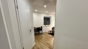 Ein Flur mit Holzboden, weißen Wänden und einem Essbereich mit Stühlen und einem Tisch.