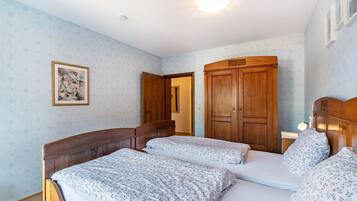 A bedroom with two beds, wooden wardrobe, and a framed picture on the wall.