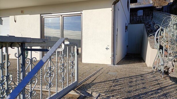 A building with a metal gate, a door, and a staircase leading to a balcony. - Apartment 'Bamboleo' with Shared Terrace, Private Garden and Wi-Fi (Veringendorf)