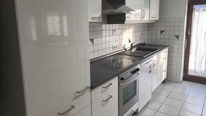 A modern kitchen with white cabinets, a stainless steel range, and a tiled backsplash. - Apartment 'Bamboleo' with Shared Terrace, Private Garden and Wi-Fi (Veringendorf)