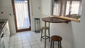 A kitchen with a tiled floor, a wooden counter, a stove, and a window with curtains. - Apartment 'Bamboleo' with Shared Terrace, Private Garden and Wi-Fi (Veringendorf)