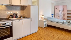 A compact kitchen with a built-in oven, a sink, and a countertop with coffee-making equipment. - Studio Apartment ' In der Stadt und Natur' with Wi-Fi (Calw)