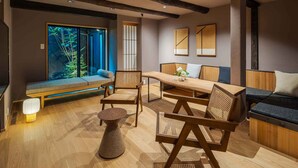 Ein modernes Interieur mit einem Holzespeisetisch, gepolsterten Sitzmöglichkeiten und einem großen Fenster mit Blick auf Grünflächen.