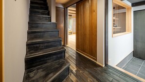 Eine Treppe führt zu einem Raum mit einer Holztür und Blick auf einen Raum mit einem Bett.