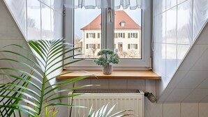 Een kamer met een raam, radiator en een kamerplant.