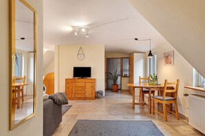 Ein Wohnzimmer mit Fernseher, Holzmöbeln, einem Essbereich und einem großen Spiegel.