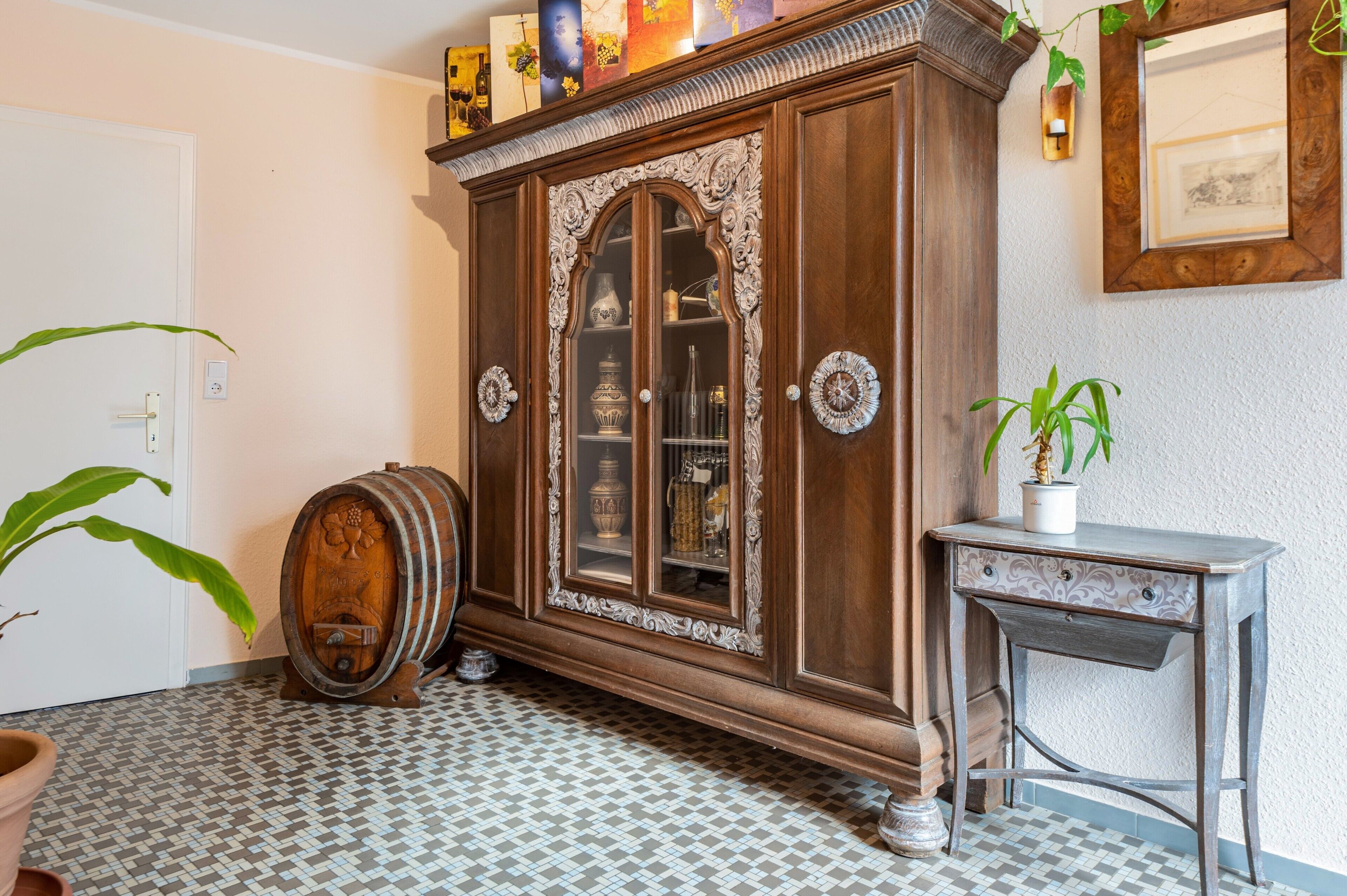 A room with a large wooden cabinet, a small table, and a potted plant.