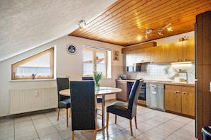 Une cuisine moderne avec des meubles en bois, une table à manger avec des chaises, un lave-vaisselle encastré et une fenêtre offrant une belle vue.
