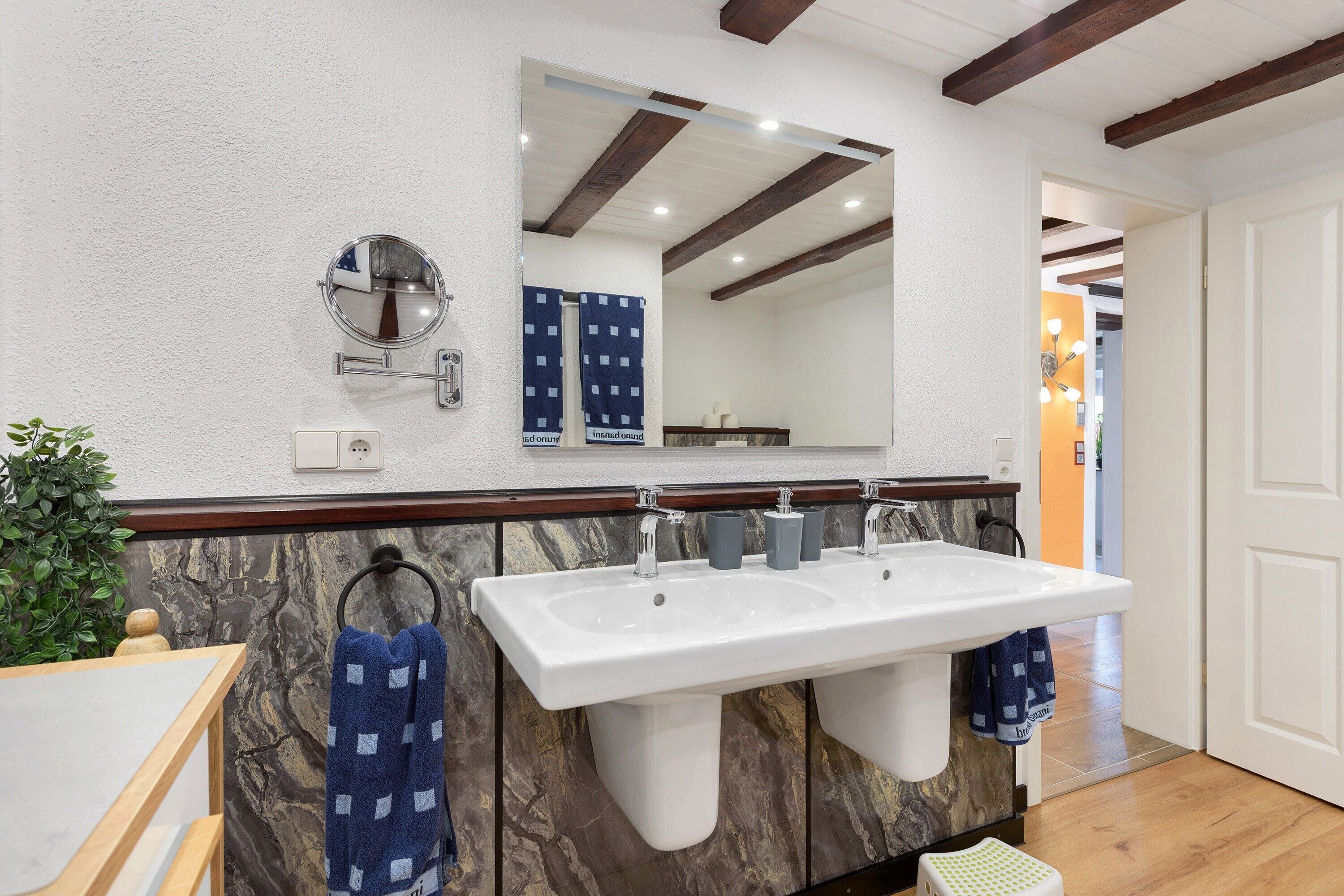 A bathroom with a white sink, two faucets, a mirror, and a towel rack.
