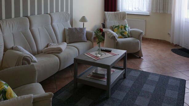 Ein Wohnzimmer mit Sofa, Sesseln, Couchtisch und einem fensterbepflanzten Fenster.