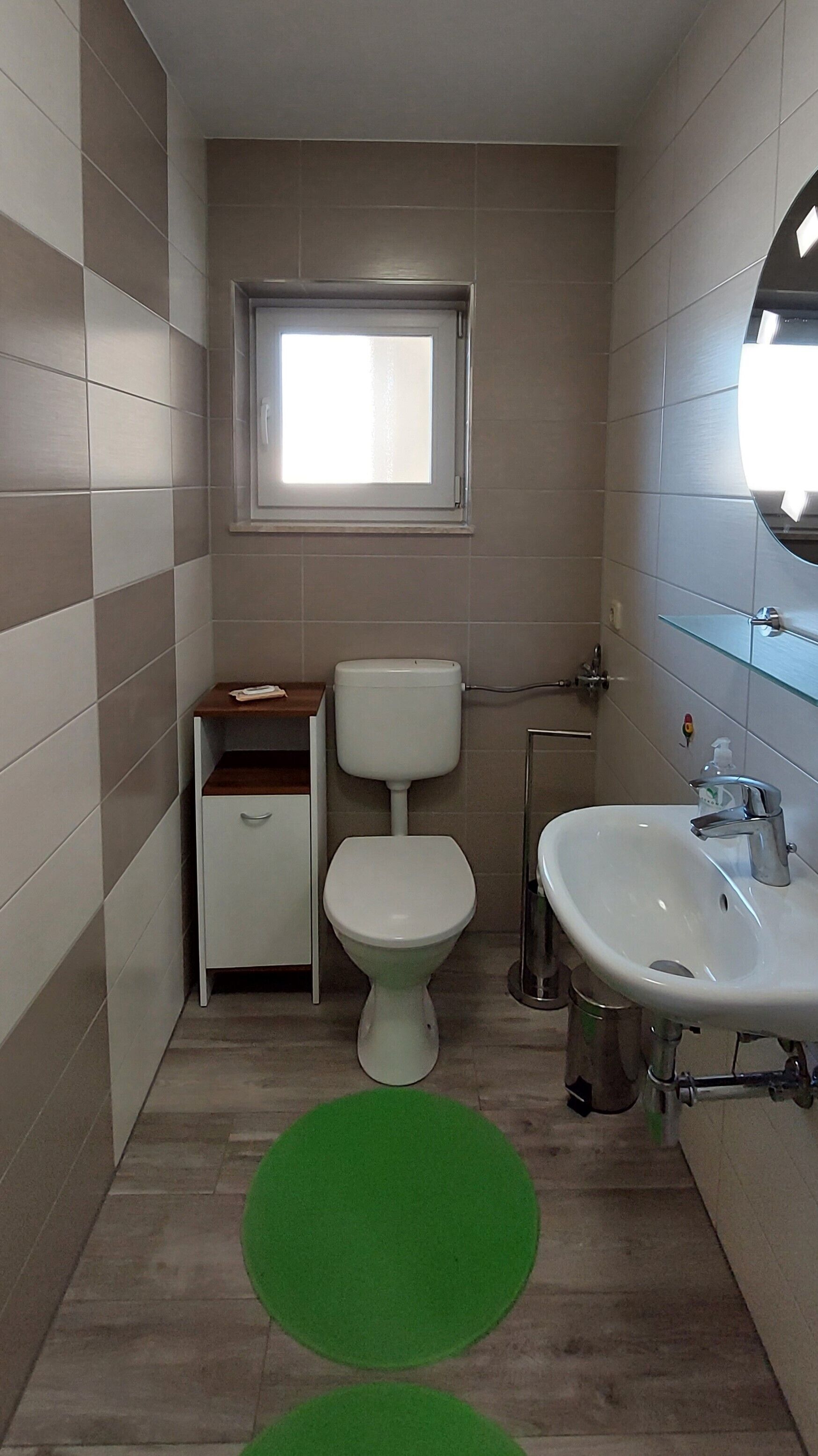 Une petite salle de bain avec des toilettes, un lavabo et une fenêtre.