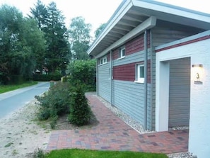 Un bâtiment moderne doté d’une porte de garage, d’un chemin en briques et d’un petit espace jardin.