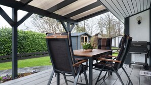 Une terrasse extérieure avec une table et des chaises, un barbecue et une vue sur le jardin.