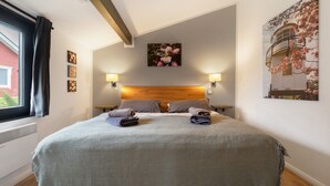 Un lit bien fait, avec des oreillers, une tête de lit et des lampes fixées au mur.