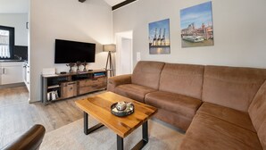 Un salon moderne avec un canapé, une table basse, un téléviseur et des œuvres d’art accrochées au mur.