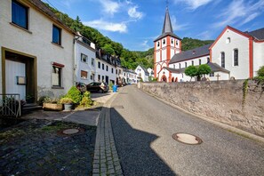 A cobblestone street lined with traditional European buildings, including a church with a tall steeple.