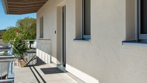 Ein modernes Gebäude mit überdachter Loggia, großen Fenstern und einer Zimmerpflanze.