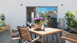 Ein Holztisch mit Stühlen, einer Blumenvase und Weingläsern auf einer Terrasse.