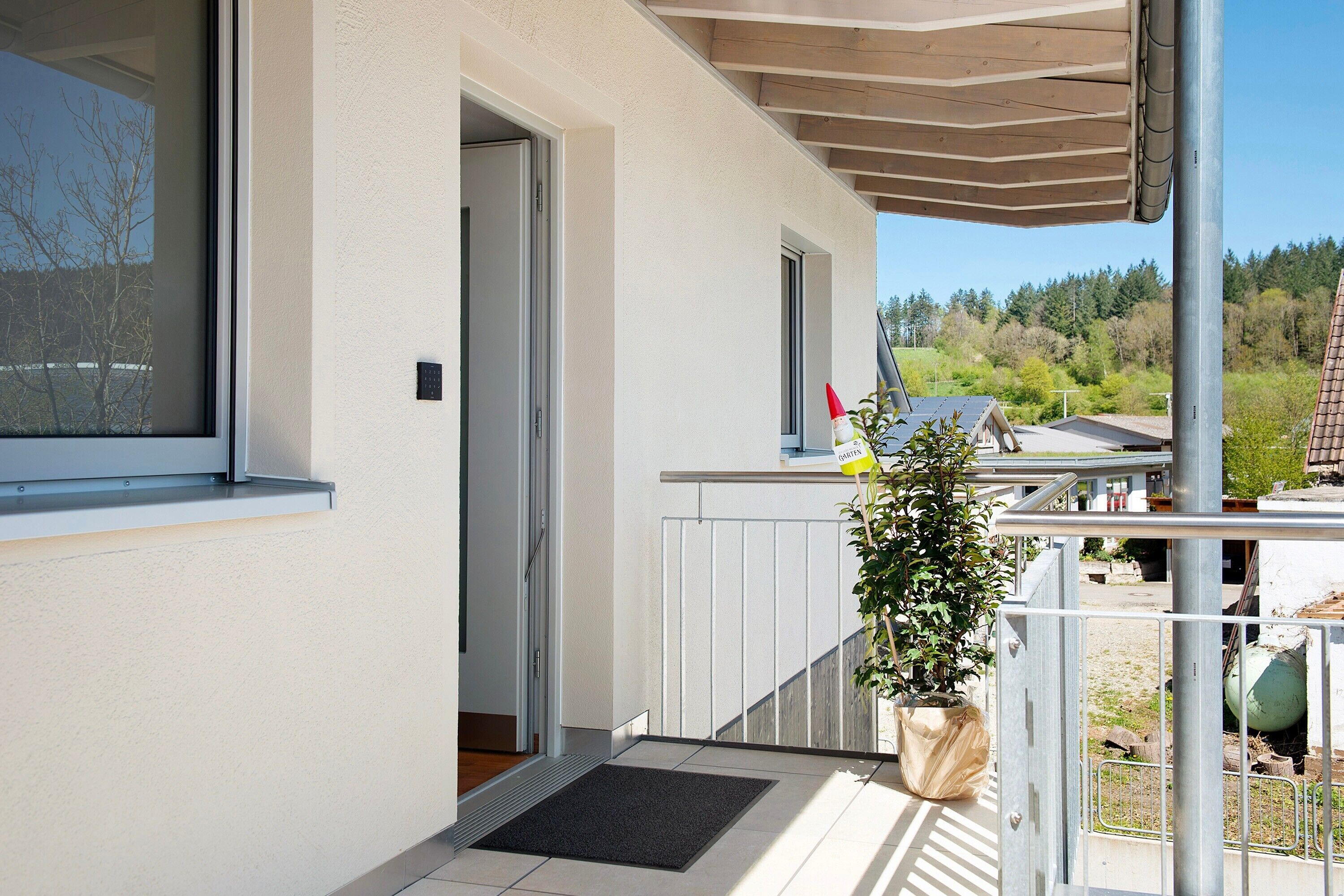 Een modern gebouw met een balkon, een deur en een bloempot.