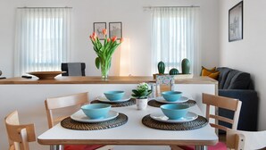 Ein Essbereich mit einem Tisch für vier Personen, Stühlen, einer Vase mit Blumen und einem Kaktus auf der Fensterbank.