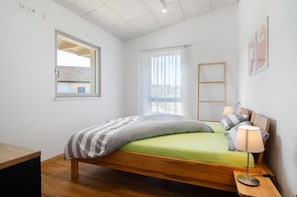 A single bed with a wooden frame, a bedside table with a lamp, a window with a view, and a wall-mounted shelf. - Deluxe Apartment 'Ahorn' with Shared Terrace, Balcony and Wi-Fi (Pfullendorf)