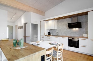 A modern kitchen with white cabinetry, a wooden countertop, and a built-in oven. - Deluxe Apartment 'Zeder' with Shared Terrace, Balcony and Wi-Fi (Pfullendorf)