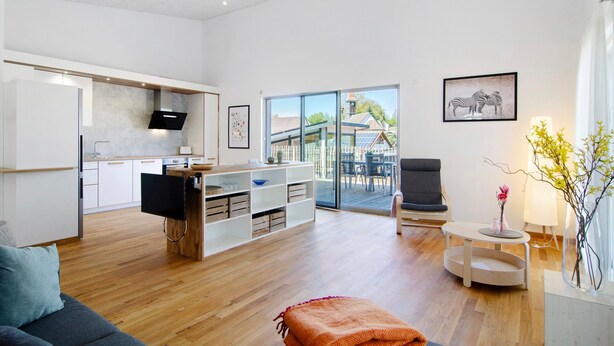 Een moderne woonkamer met een bank, een televisie, een salontafel en een eethoek met een tafel en stoelen.
