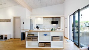 Een moderne keuken met een centraal eiland, inbouwapparatuur en een groot raam met uitzicht op de omgeving.