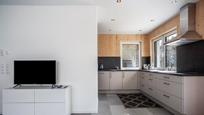 A modern kitchen with white cabinetry, a built-in stove, and a large window with blinds. - Holiday Apartment 'Wohnen an der Ach' with Private Garden, Balcony and Wi-Fi (Bad Wurzach)