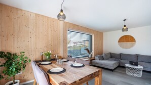 A modern living room with a wooden dining table, grey sofa, and a potted plant. - Holiday Apartment 'Wohnen an der Ach' with Private Garden, Balcony and Wi-Fi (Bad Wurzach)