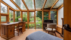 Quarto com teto de vidro amplo, mobiliário de madeira e vista para um jardim.