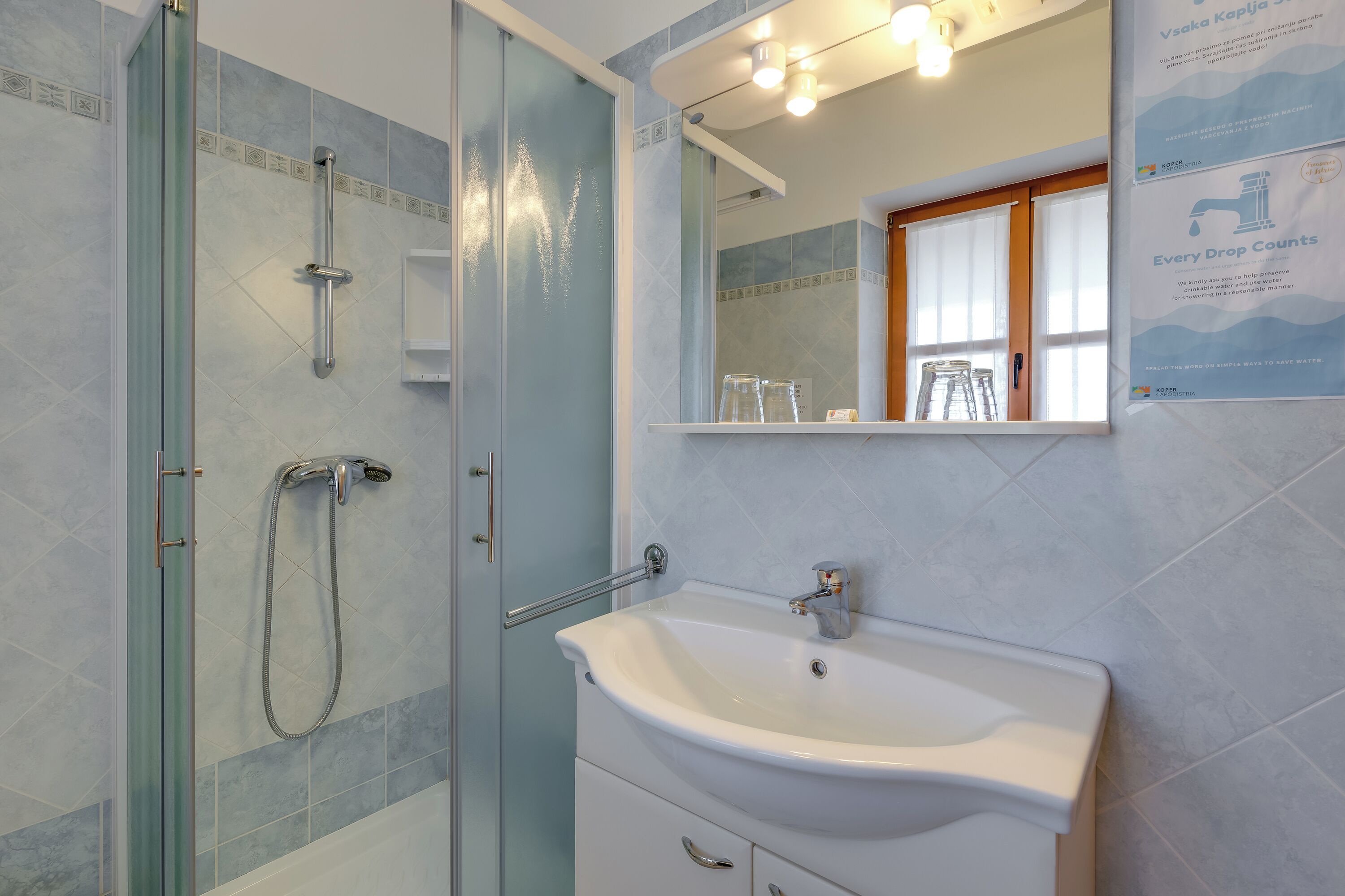 A bathroom with a glass shower enclosure, a white sink, and a mirror above it.
