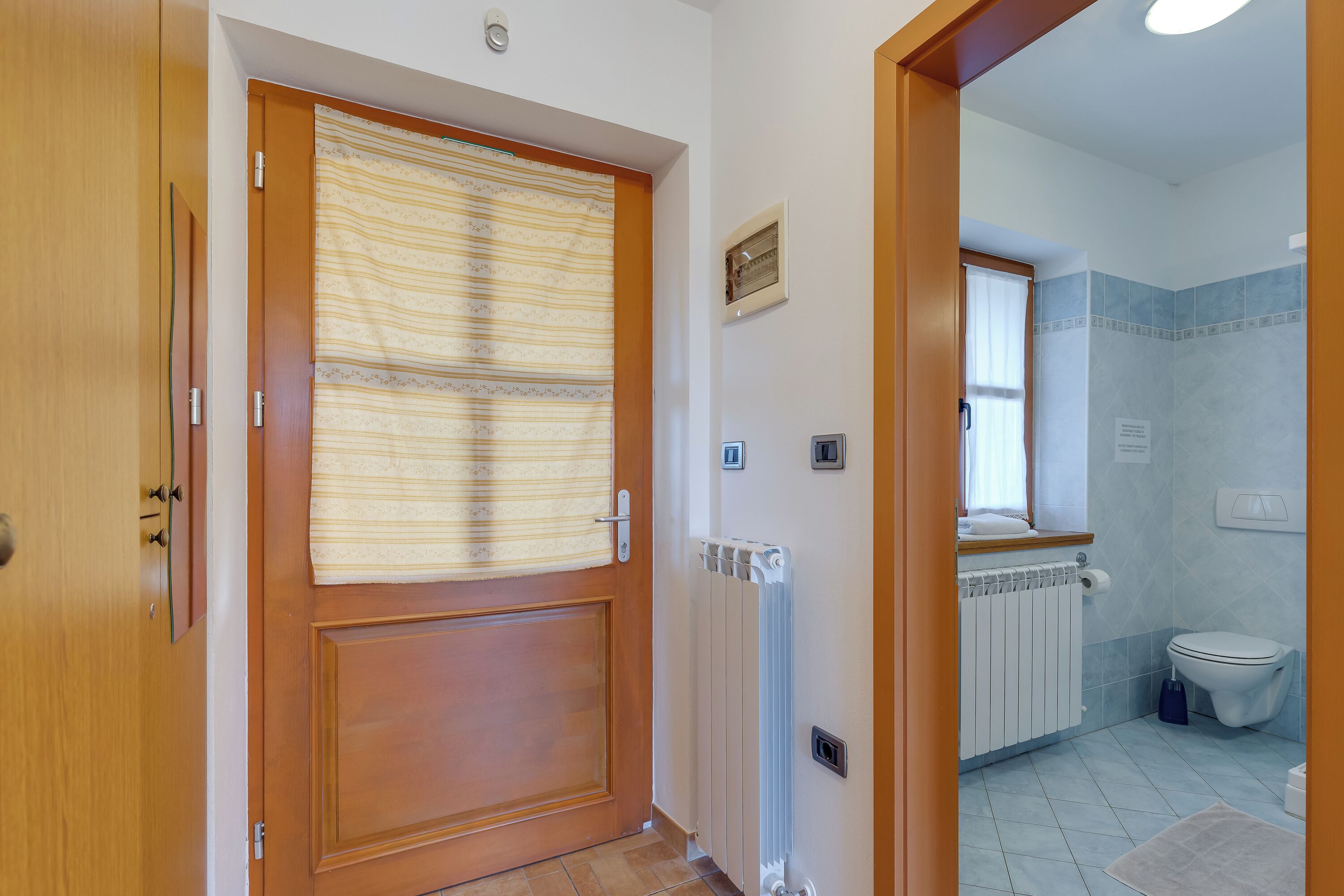 Une salle de bain avec des toilettes, un radiateur et une fenêtre.