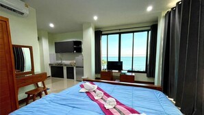 Habitación de hotel con cama, escritorio, televisor y vista al mar.