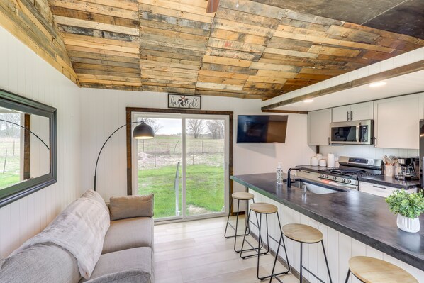 A modern kitchen with a large island, bar stools, and a flat-screen TV.