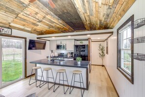 A modern kitchen with a large island, bar stools, and a view of the outdoors.
