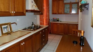 A kitchen with wooden cabinets, a gas stove, a sink, and a dining table with chairs.